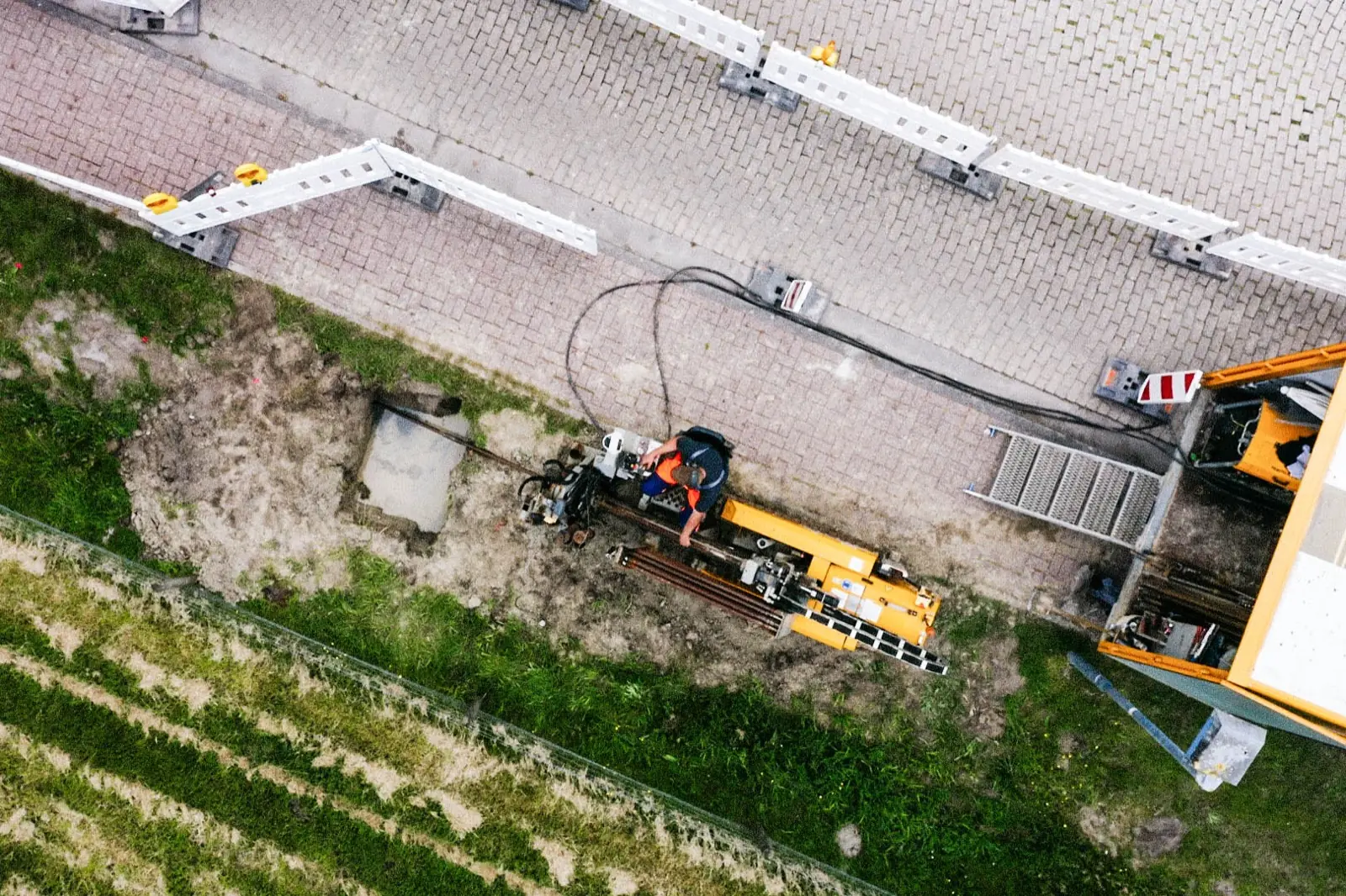 Luftaufnahme einer gesteuerten Horizontalbohranlage neben einem Gehweg